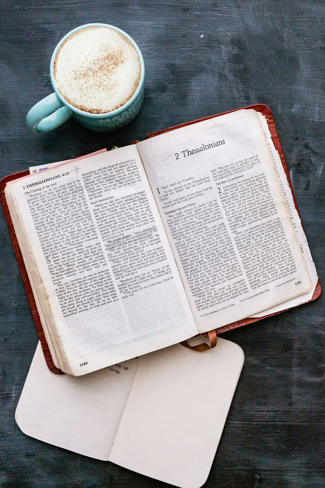 Open notebook with handwritten notes beside a cup of coffee