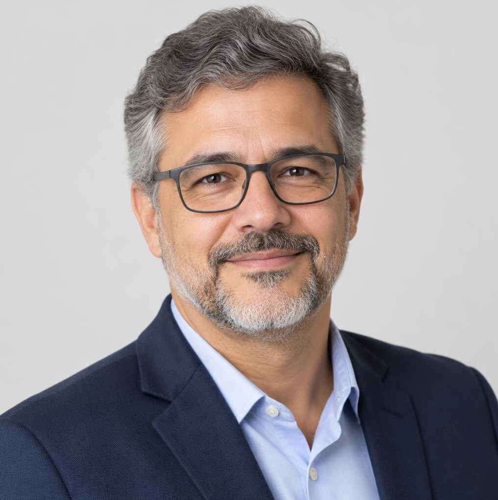 Studio portrait of an older Brazilian man with glasses smiling